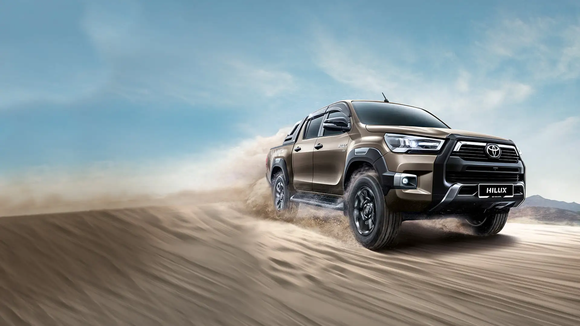Toyota Hilux double cab showcasing off-road capability with alloy wheels on challenging rocky outcrop at golden hour