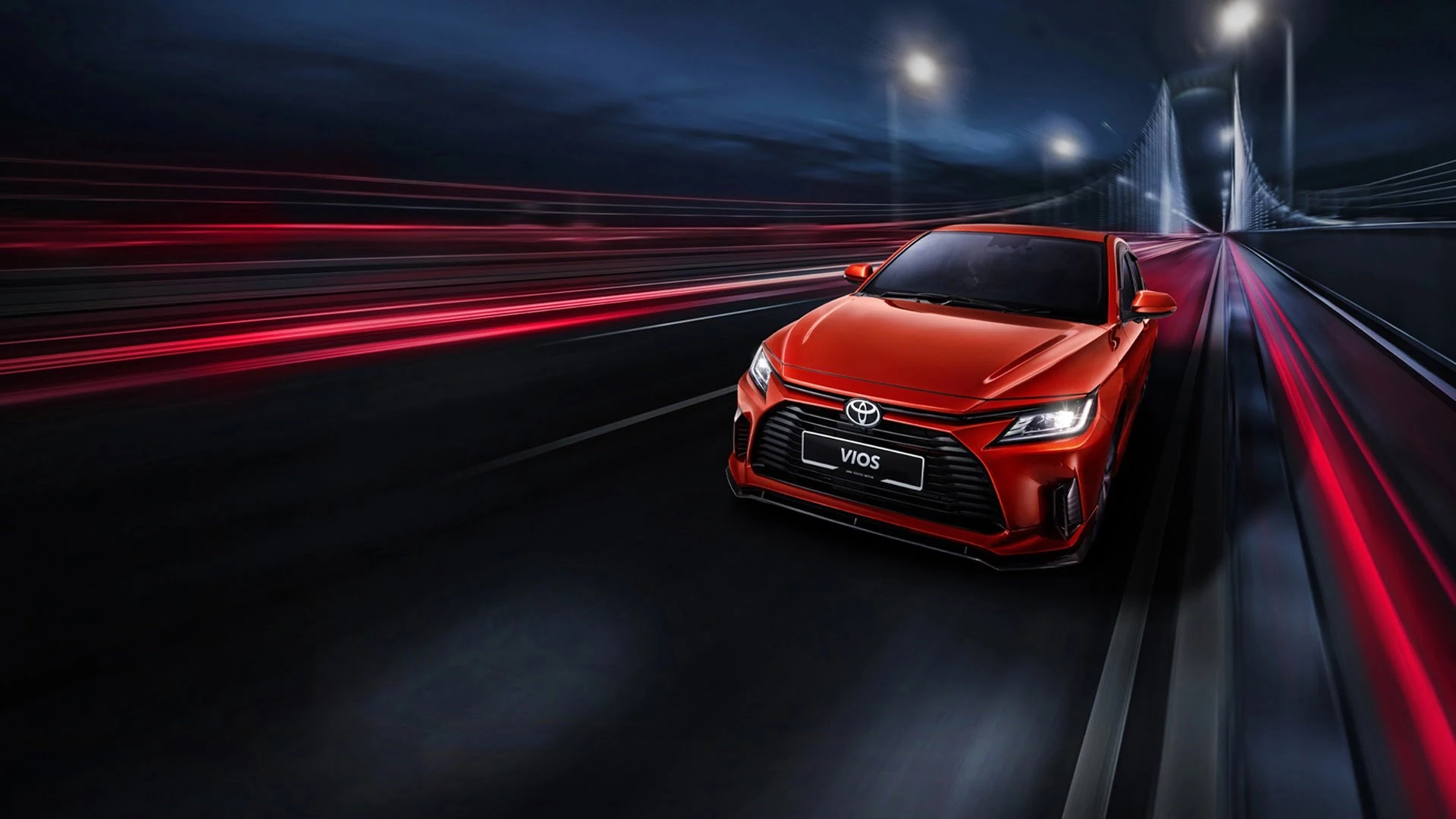 Red Toyota Vios sedan driving on illuminated highway with dynamic light trails and modern bridge backdrop