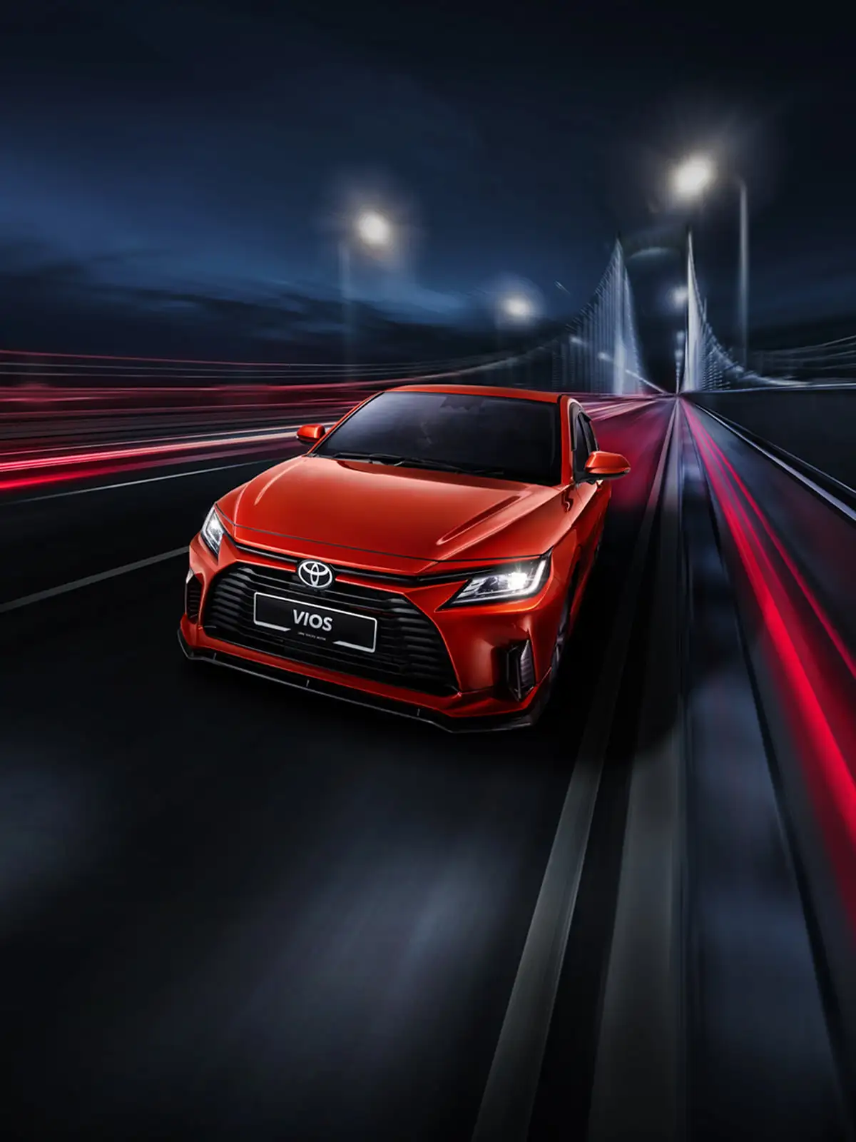 Red Toyota Vios sedan driving on illuminated highway with dynamic light trails and modern bridge backdrop